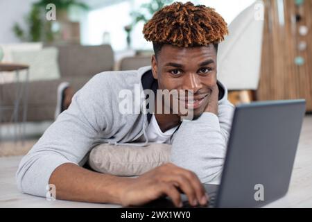 happy man laying down on the floor using laptop Stock Photo