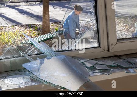 KYIV, UKRAINE - MARCH 26, 2024 - A woman removes the debris as seen through glass shards at the Mykhailo Boichuk Kyiv State Academy of Decorative and Applied Arts and Design in the Pecherskyi district that was destroyed by the falling debris of a downed Russian ballistic missile, Kyiv, capital of Ukraine. As reported, Russian troops launched two ballistic missiles at the Ukrainian capital on Monday, March 25, at approximately 10:30 local time. Stock Photo