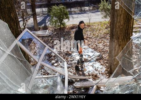 KYIV, UKRAINE - MARCH 26, 2024 - A woman picks up glass shards at the Mykhailo Boichuk Kyiv State Academy of Decorative and Applied Arts and Design in the Pecherskyi district that was destroyed by the falling debris of a downed Russian ballistic missile, Kyiv, capital of Ukraine. As reported, Russian troops launched two ballistic missiles at the Ukrainian capital on Monday, March 25, at approximately 10:30 local time. Stock Photo