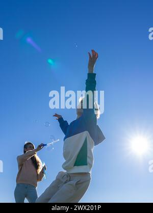 mother and son playing with soap bubbles outdoors Stock Photo