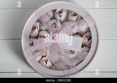 Zephyr in a box. Marshmallow tulips. The box is pink, tied with a ribbon. It stands on a white table. Taken from above. Stock Photo
