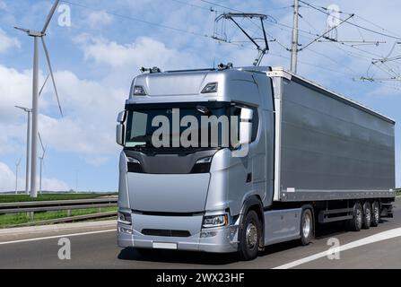 Electric semi truck with pantograph takes energy from wires above the highway. Stock Photo