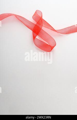 Red tulle ribbon with waves on top  on white isolated background. Top view. Stock Photo