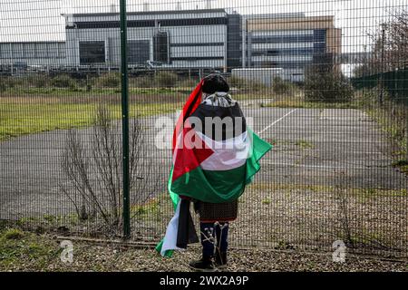 Sandwich, UK. 26th Mar, 2024. A supporter of the activists gazes through the fence towards Instro Precision wearing a Palestinian flag as a cape. Instro Precision provide components for Elbit Systemís weaponry. Palestine Action continues to target subsidiary companies of Israeli arms company Elbit Systems in an attempt to isolate them and make business impossible. This tactic has caused two of Elbit's ten main businesses to close in the UK and several partner companies to cut ties with them. Credit: SOPA Images Limited/Alamy Live News Stock Photo
