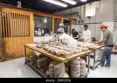 Multi-ethnic group of colleagues working in a bread factory, teaching the apprentices Stock Photo