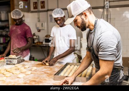 two men young black classmates learning how to make cakes from master pastry chef at bread factory Stock Photo