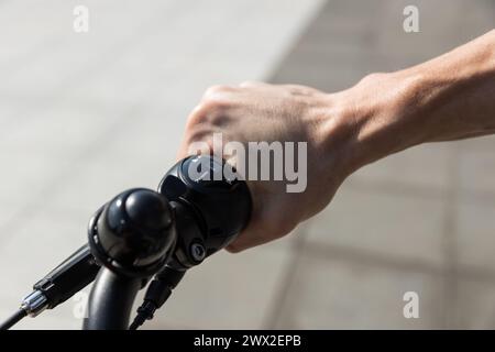unrecognizable young man rides e-bike, hands holding bicycle handlebars Stock Photo
