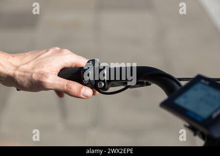 unrecognizable young man rides e-bike, hands holding bicycle handlebars Stock Photo