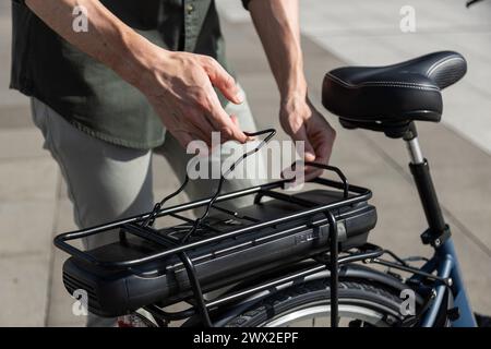 young businessman rides e-bike on his way to the tower where his office is located Stock Photo