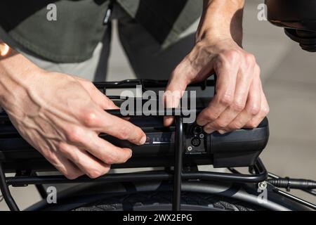 young businessman rides e-bike on his way to the tower where his office is located Stock Photo