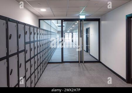 School corridor with glass partitions and lockers. Fulham Boys School, Fulham, United Kingdom. Architect: Architecture Initiative, 2021. Stock Photo