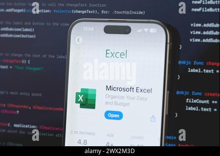 New York, USA - February 23, 2024: Microsoft Excel  on iphone screen in blurred code programming background Stock Photo