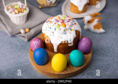 Easter kulich with candied fruits in white glaze with colorful sprinkles and painted eggs. Traditional Easter pastry. Easter holiday. Close-up, select Stock Photo