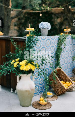 Wicker boxes with tangerines stand near a festive stand with bouquets of flowers in vases Stock Photo
