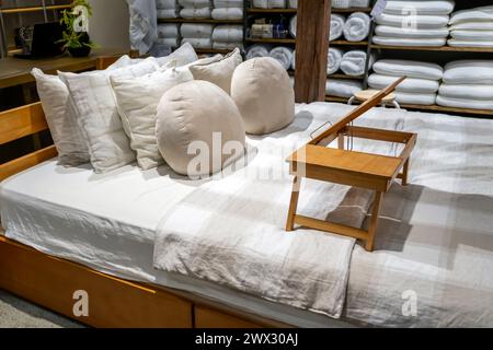 Double beds with glazed linens, duvet, sheets and pillows in furniture store. Table for bed eat food morning breakfast. Stock Photo