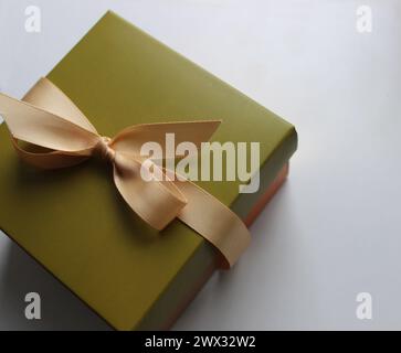 Gift wrapping in olive tones with an elegant beige ribbon on a clean white sheet of paper Stock Photo