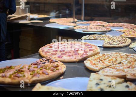 This image shows a variety of gourmet pizzas with different toppings, ready to be served in a warm and inviting pizzeria atmosphere. The pizzas are at Stock Photo
