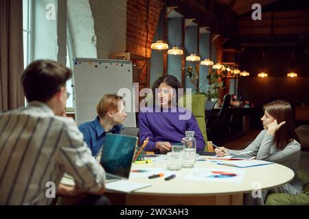 Test preparation. Young people, students site at table with laptops and papers, studying together and preparing for exams Stock Photo