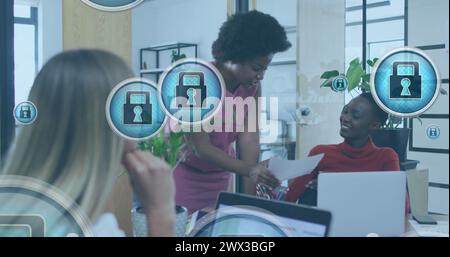 Image of padlock in circles over diverse female coworkers discussing reports in office. Digital composite, multiple exposure, business, protection, pl Stock Photo