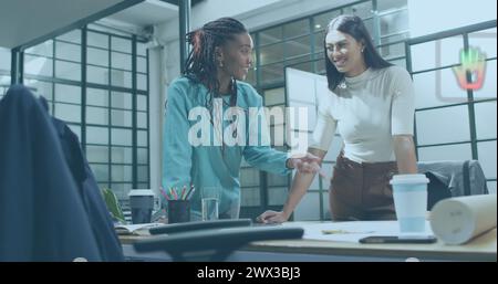 Image of multiple icons over diverse female architects discussing floor plan and shaking hands. Digital composite, multiple exposure, business, planni Stock Photo
