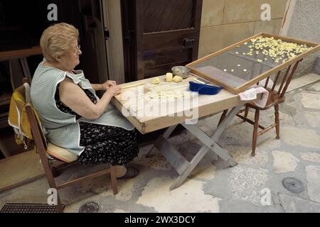 woman making traditional fresh pasta called "orecchiette" in a street of Bari Old Town Stock Photo
