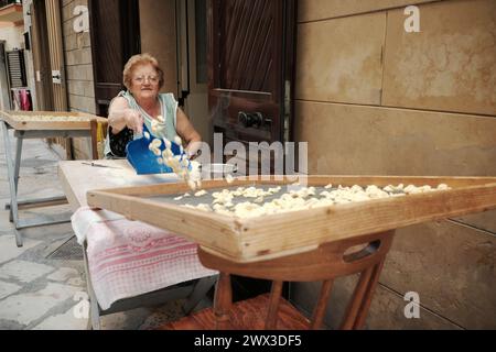 woman making traditional fresh pasta called 'orecchiette' in a street of Bari Old Town Stock Photo