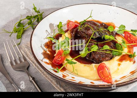 Mashed potatoes with beef in sweet and sour sauce, decorated with tomatoes and microgreens. Restaurant lunch. Copy space Stock Photo