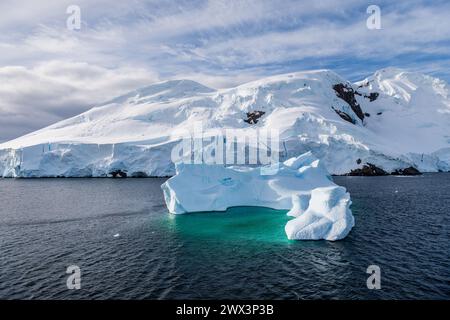 A tranquil Antarctic landscape, near Graham passage along Charlotte Bay, highlighting stark reflections, rugged mountains, and impressive icebergs. Stock Photo