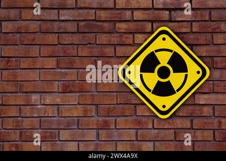 Radioactive sign on brick wall, space for text. Hazard symbol Stock Photo