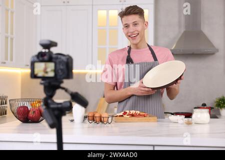 Smiling food blogger explaining something while recording video in kitchen Stock Photo
