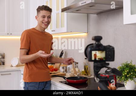 Smiling food blogger explaining something while recording video in kitchen Stock Photo
