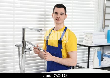 Portrait of smiling plumber repairing faucet in bathroom Stock Photo