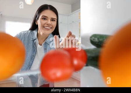Thoughtful woman near refrigerator in kitchen, view from inside Stock Photo