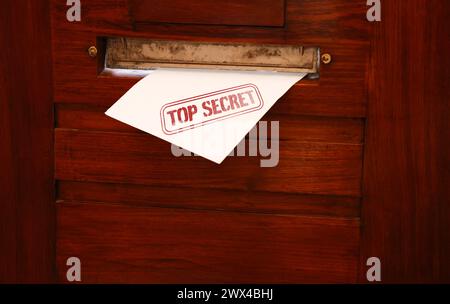 Top Secret stamp. Mail slot with envelope in wooden door Stock Photo