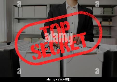 Top Secret stamp. Woman taking documents from folder in archive, closeup Stock Photo