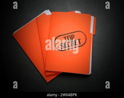 Top Secret stamp. Orange files with documents on black table, top view Stock Photo