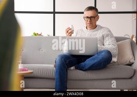 Middle-aged man checking pills description online at home Stock Photo