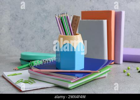 Pencil holder and notebooks on table against grey background Stock Photo