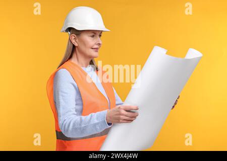 Architect in hard hat with draft on orange background Stock Photo