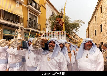 Almuneca, Spain.  Easter week in Almuneca, Spain commences with the first major event is Palm Sunday (Domingo de Ramos), the holiday held exactly one week before Easter Sunday, commemorating Jesus' famed entry into Jerusalem on a donkey. The brotherhoods organise the processions that parade through the streets and squares every day carrying beautiful 'pasos' and 'tronos' adorned with flowers and religious images that are carried on the shoulders of the participants.Here they are exiting the Church of the Encarnación in Almuñécar at the beginning of the parade. 24th March 2024 David Smith/Alamy Stock Photo