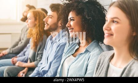 Diverse millennial group sitting in row, waiting for something Stock Photo