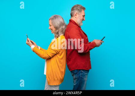 Elderly man and woman scrolling on their cell phones, studio Stock Photo