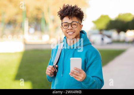 Smiling student using phone in city Stock Photo