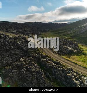 A view of the dirt road stretching to the horizon among the lava fields. Top view, photo taken from the drone. Helgafellssveit, Iceland. Stock Photo