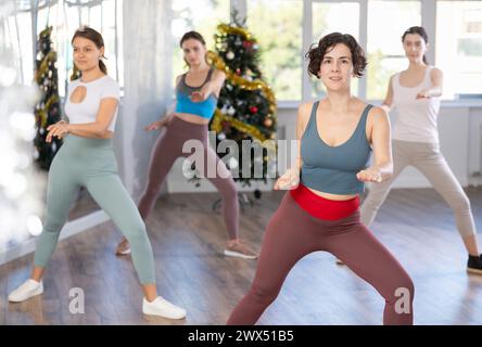 Enthusiastic Hispanic woman leading dance fitness class during Christmas season Stock Photo