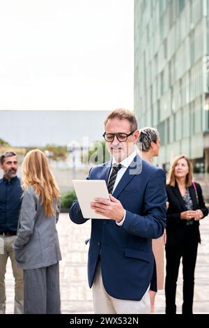 A middle-aged Caucasian man worker in formal attire, standing in front of a crowd Stock Photo