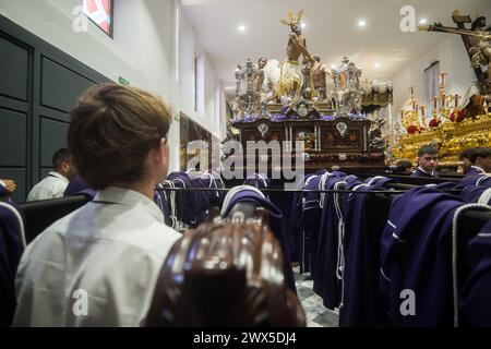 Malaga, Spain. 27th Mar, 2024. A penitent from 'Fusionadas' brotherhood is seen looking at the statue of Christ, after the procession was suspended due to the rain, during Holy Wednesday, to mark the Holy Week celebrations. Thousands of worshippers wait to see the processions with the statues of Christ and the Virgin Mary as part of the traditional Holy Week celebrations. In Andalusia, Easter brings together thousands of people from all over the world and it's considered one of the most important religious and cultural events of the year. Credit: SOPA Images Limited/Alamy Live News Stock Photo