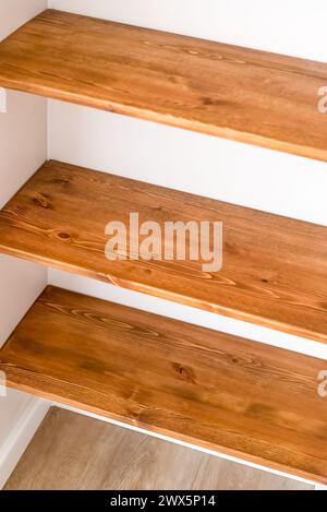 Three white shelves on wooden interior texture background, stock photo ...