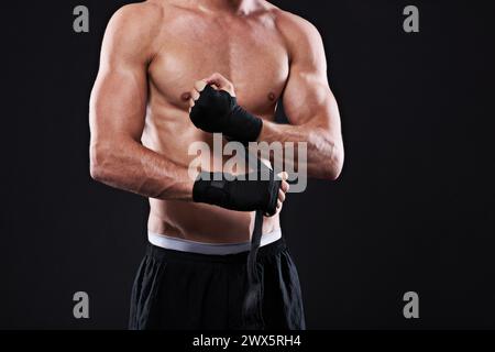 Wrapping, hands and man in martial arts for boxing on black background in studio with preparation closeup. Tape, fist and ready to start training as Stock Photo