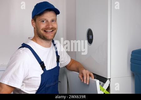 smiling maintenance and repair service engineer working with house gas heating boiler Stock Photo
